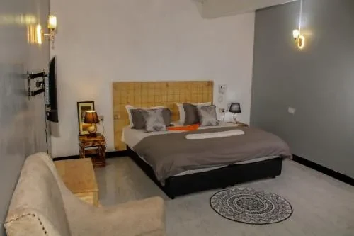 A guest room with a king bed, armchair and TV