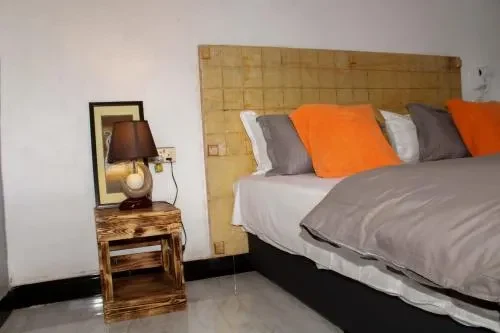 Bed with orange cushions and a wooden bedside table